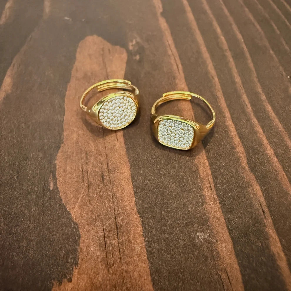 Gold pavé statement rings on dark wood surface