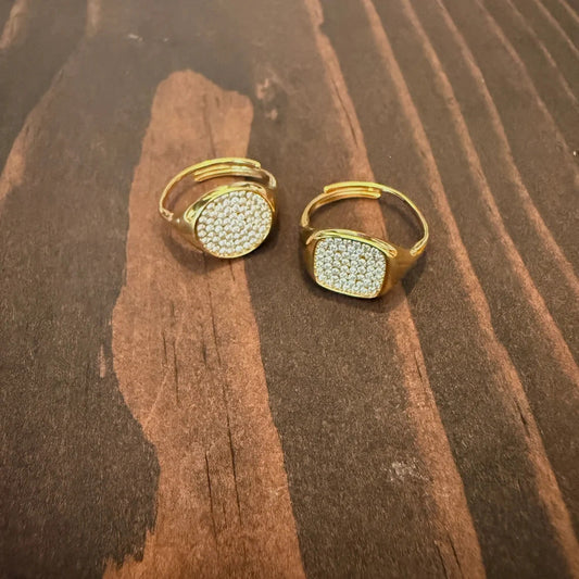 Gold pavé statement rings on dark wood surface