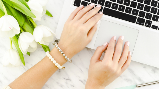  Hands of a woman wearing two types of pearl bracelets