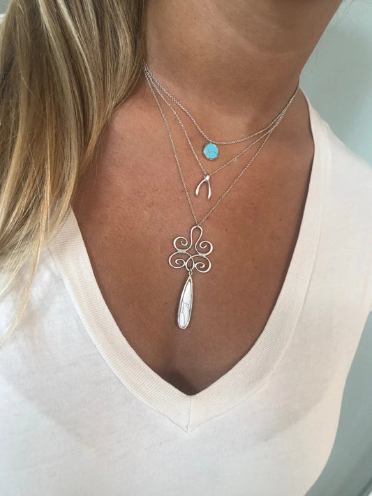 Layered silver necklaces with turquoise, wishbone charms