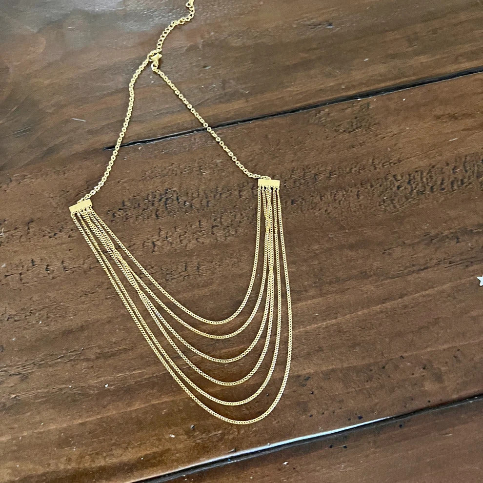 Multi-strand layered gold chain necklace on wood