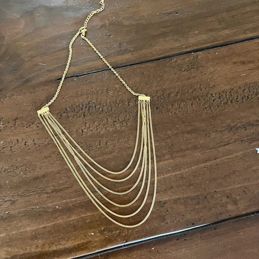 Multi-strand layered gold chain necklace on wood