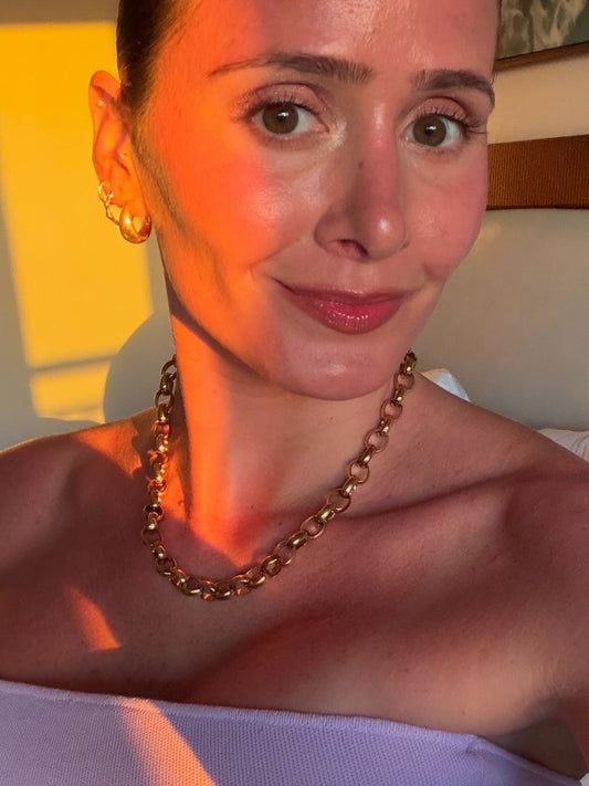 Woman wearing gold plated hoop earrings and chain necklace
