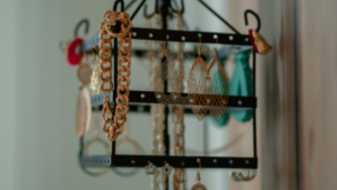 A compact black tabletop jewelry stand holding necklaces, earrings, bracelets, and chains,